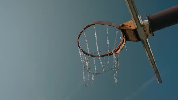 Basketbal bal krijgt in de ring tegen een blauwe hemel achtergrond — Stockvideo