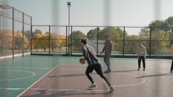 Fyra unga män kastar basket på en plan i parken på en solig dag — Stockvideo