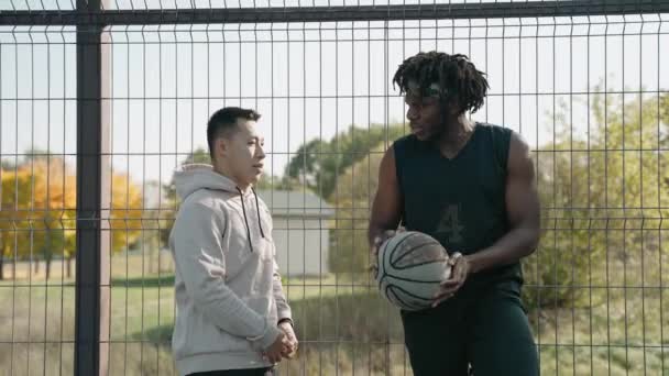 Jungs versammeln sich auf einem Platz, um an einem sonnigen Herbsttag Basketball zu spielen — Stockvideo