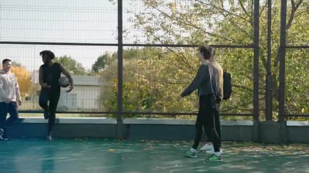 Хлопці збираються разом на корті, щоб грати в баскетбол в сонячний осінній день — стокове відео