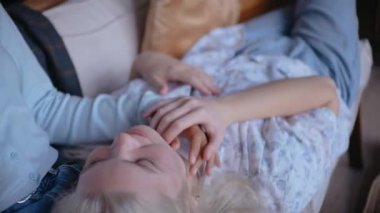 Kız arkadaşının kucağında kanepede uzanmış, ellerinle oynuyor.