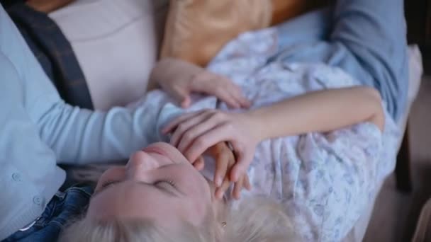 Fiatal lány feküdt az ölében barátnője a kanapén, játszik a kezével — Stock videók