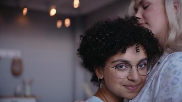Schwarzes Mädchen umarmt und küsst ihre Freundin, lacht und blickt in die Kamera — Stockvideo
