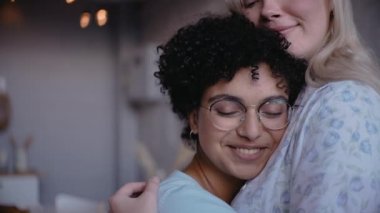 Siyah kız kız kız arkadaşıyla sarılıyor gülümsüyor ve kameraya bakıyor. 