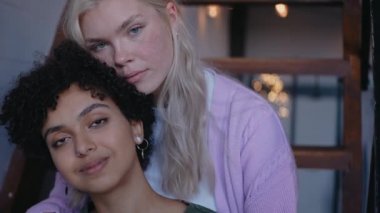 Kız arkadaşına arkadan sarılıyor ve kameraya bakarak gülümsüyor..