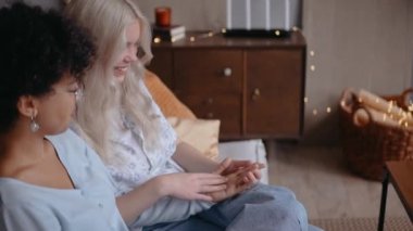 Kızlar kanepede otururken el ele tutuşuyorlar.