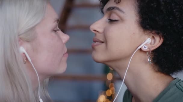 Молоді дівчата слухають музику в навушниках і цілують на носі, танцюють і посміхаються — стокове відео