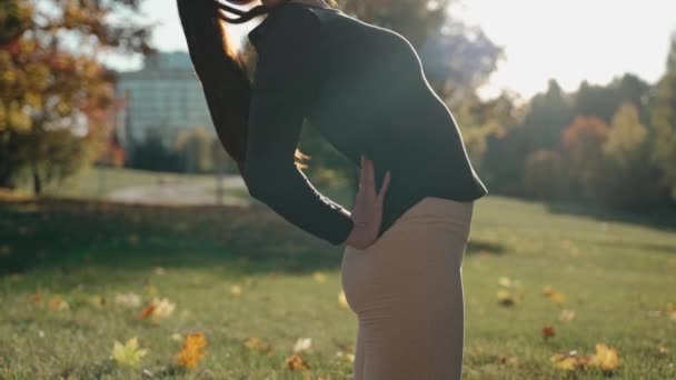 Fechar tiro de jovem mulher arqueando para trás no parque de outono em um tapete de ioga — Vídeo de Stock