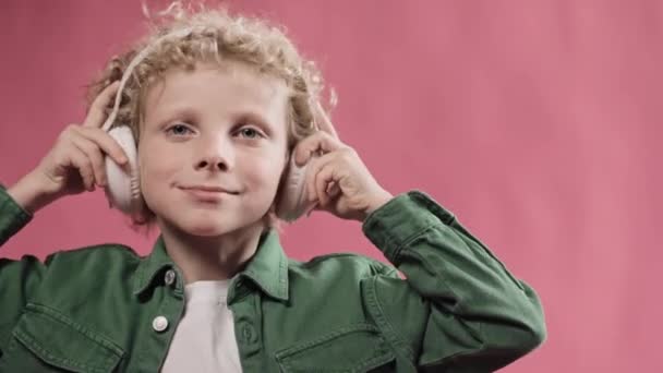 Маленький блондинка носить великі навушники і киває головою — стокове відео