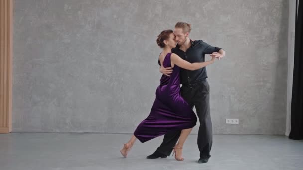 Man and woman are sensually doing tango pose in grey studio — Stock Video