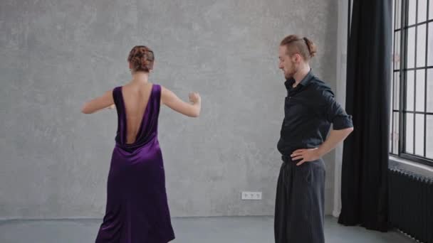 Mężczyzna uczy kobieta taniec tango w szary studio przeciw Duży okna — Wideo stockowe