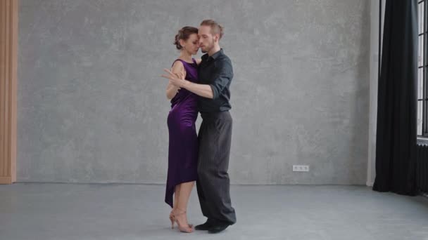 Man and woman are sensually doing tango pose in grey studio — Stock Video