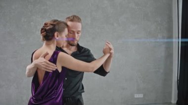 Erkek ve kadın, gri odada duygusal bir şekilde tango yapıyor.