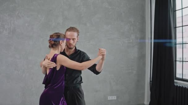 Mężczyzna i kobieta aktywnie i zmysłowo tańczą tango w szarym pokoju — Wideo stockowe