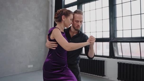Tiro de mulher sentada em uma perna de homem dançando um tango em estúdio cinza — Vídeo de Stock
