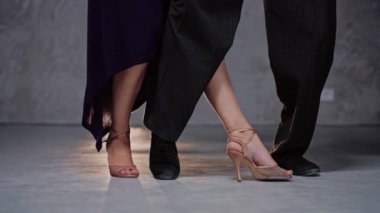 Gri stüdyoda tango çalışması yapan iki dansçı bacağı.