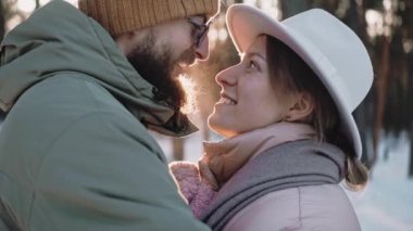 Romantik, şık bir çift, güneşli bir kış gününde ormanda konuşur ve öpüşür.