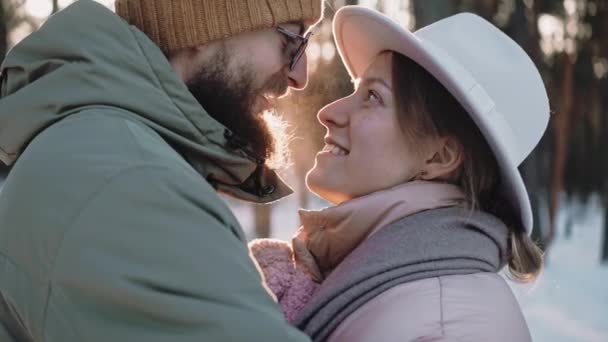 Романтическая стильная пара разговаривает и целуется в лесу в солнечный зимний день — стоковое видео