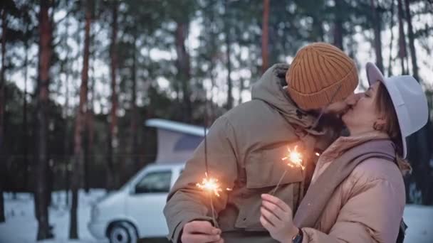 Щаслива пара легких блискіток і поцілунок в лісі взимку, насолоджуючись життям фургона — стокове відео