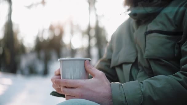 Hombres sosteniendo una taza con bebida caliente en el bosque en un día soleado de invierno en el campamento — Vídeos de Stock