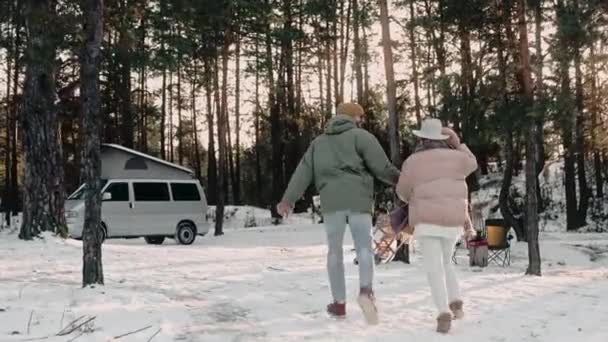 Романтическая пара счастливо ходит по деревянному лагерю, держа за руки, наслаждаясь жизнью фургона — стоковое видео
