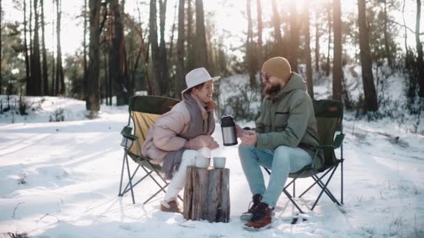 Pasangan romantis minum dan berbicara di hutan di musim dingin, menikmati kehidupan kamp — Stok Video