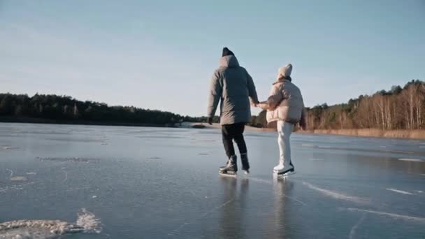 Couple is skating on a clear frozen lake on a sunny day with beautiful landscape — Stock Video