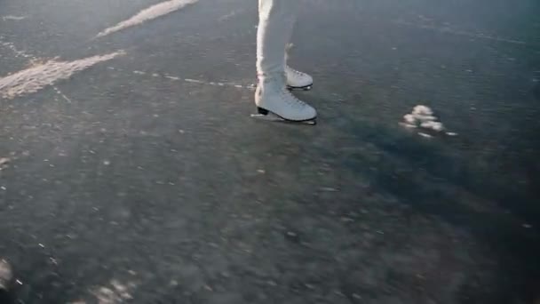 Mujer patinaje sobre hielo en un lago congelado claro en un día de invierno soleado en pantalones blancos — Vídeos de Stock