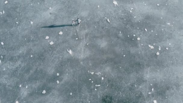 Tinggi foto udara pasangan skating di danau beku dalam pemandangan cerah yang indah — Stok Video