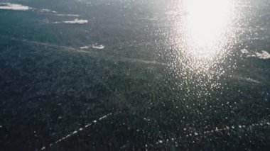 Mavi, berrak, derin çatlaklarla donmuş gölde paten izleri var.