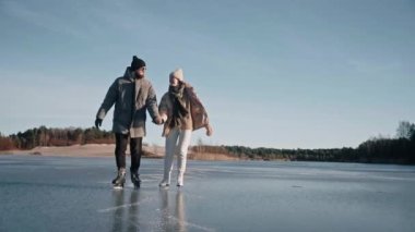 Çiftler güneşli bir günde açık bir gölde paten kayıyorlar.