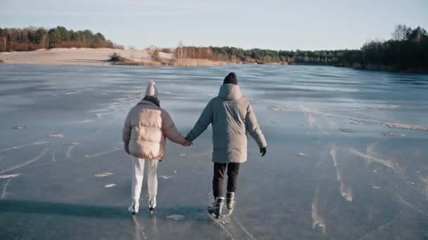 Luftaufnahme eines Paares beim Schlittschuhlaufen auf einem klaren zugefrorenen See an einem sonnigen Wintertag — Stockvideo