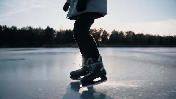 Hombre practica patinaje sobre hielo en un lago helado claro en un día soleado en la naturaleza — Vídeo de stock