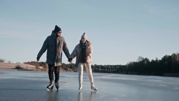Paar läuft Schlittschuh auf einem klaren zugefrorenen See an einem sonnigen Tag mit schöner Landschaft — Stockvideo
