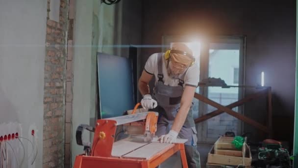 Muž stavitel používá elektrický dlaždice řezačka ve stavebním studiu — Stock video