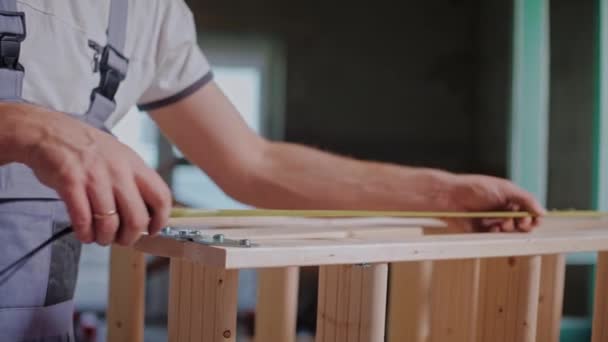 Constructor masculino utiliza una cinta métrica para medir la construcción de madera en el estudio — Vídeo de stock