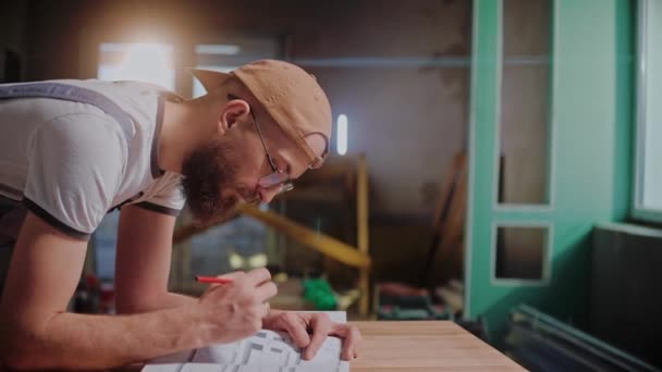Мужчина строитель чертит план строительства на бумаге большого формата — стоковое видео
