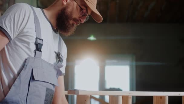 Erkek müteahhit stüdyodaki iki tahta parçayı birleştirmek için elektrikli tornavida kullanıyor. — Stok video