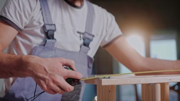 Constructor masculino usando una cinta métrica y escribiendo medidas de construcción de madera — Vídeo de stock
