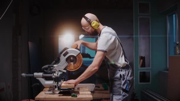 Stavitel krájí dřevěnou desku na stole kruhové pily ve stavebním studiu — Stock video
