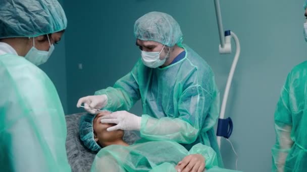 Drie chirurgen die neuscorrectie uitvoeren in groene beschermende jurken — Stockvideo
