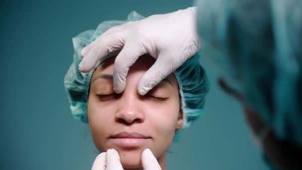 Хирург осматривает девушек перед ринопластикой в защитных перчатках — стоковое видео