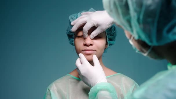 Χειρουργός εξετάζει τα κορίτσια πρόσωπο πριν από ρινοπλαστική, φορώντας προστατευτικά γάντια — Αρχείο Βίντεο
