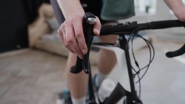 Close shot de um ciclista mudando de velocidade em uma bicicleta de exercício, treinando em casa — Vídeo de Stock
