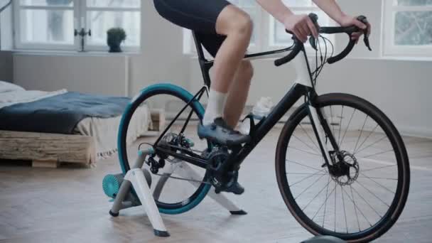 Tiro das pernas de um ciclista treinando em uma bicicleta de exercício em casa — Vídeo de Stock