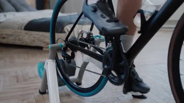 Fechar tiro de um ciclistas pernas formação em uma bicicleta de exercício em casa — Vídeo de Stock