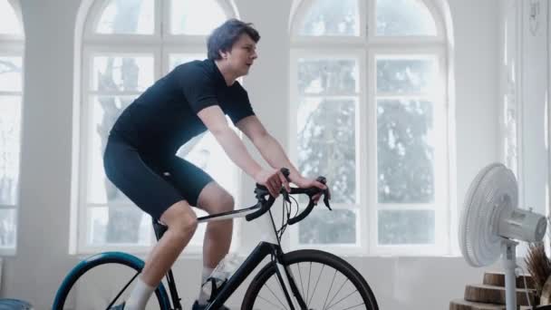 Ciclista treinando em uma bicicleta de exercício e água potável ficar em casa — Vídeo de Stock