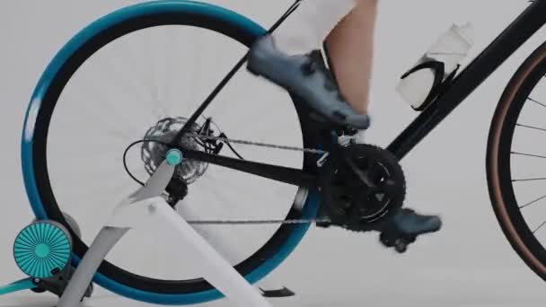 Foto ravvicinata di un ciclista che si allena le gambe su una cyclette in studio bianco — Video Stock