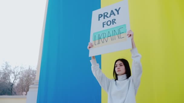 Woman Holds Poster Quote Pray Ukraine Huge Ukrainian Flag Young — Stock Video