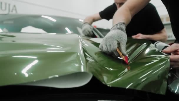 Δύο Άνδρες Τυλίγουν Ένα Αυτοκίνητο Σκούρο Πράσινο Χρώμα Χρησιμοποιώντας Πλαστικές — Αρχείο Βίντεο